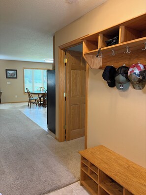 A room with a wooden bench, a wall-mounted hat rack, and a door leading to another room.