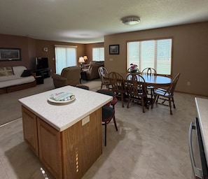 Uma sala de estar com televisão, sofá e um espaço de jantar com mesa e cadeiras.