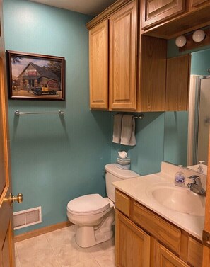 Ein Badezimmer mit Toilette, Waschbecken, Holzausbau, einem Handtuchhalter und einem gerahmten Bild an der Wand.