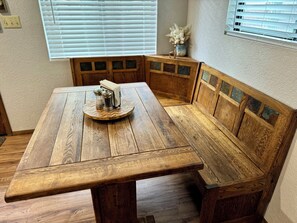A wooden dining table with a bench, salt and pepper shakers, and a book on it. - Cozy Cabin in Munds Park (Munds Park)