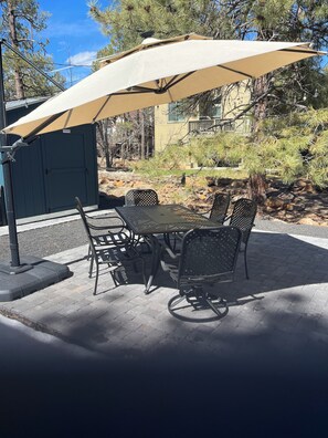 An outdoor patio with a table and four chairs under a large umbrella. - Cozy Cabin in Munds Park (Munds Park)