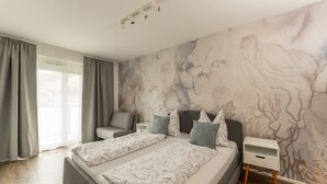 A bedroom with a large bed, a nightstand, a chair, and a mural on the wall. - APSTAY Apartments (Graz)
