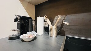 A kitchen counter with a coffee machine, a bowl of food, a napkin holder, and kitchen utensils. - APSTAY Apartments (Graz)