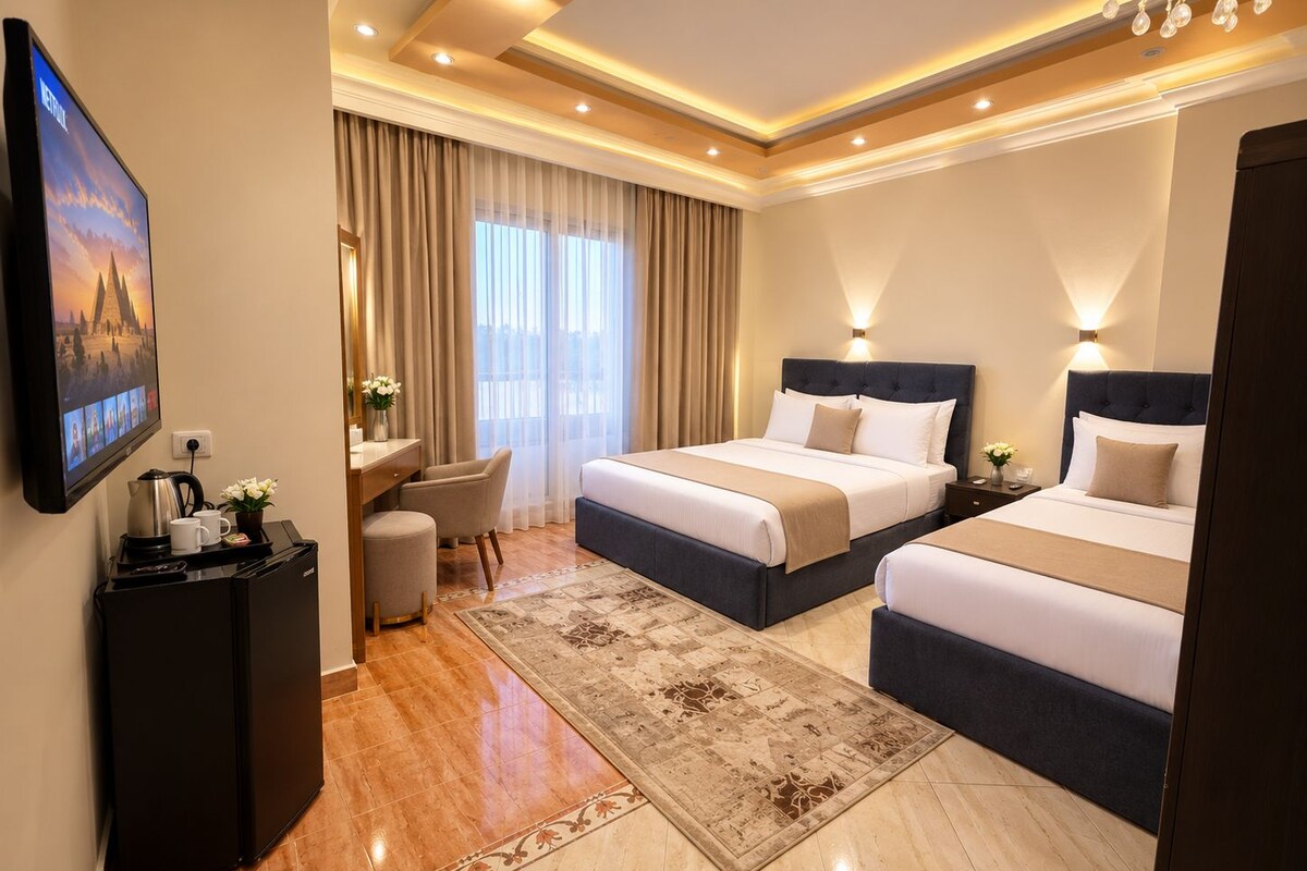 A hotel room with two beds, a desk, a TV, and a coffee maker.