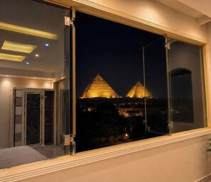 Una habitació amb una finestra gran que dona als pyramids de nit.