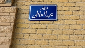 A blue sign with Arabic text on a yellow brick wall. - ZEINA PYRAMIDS VIEW HOTEL (Giza)