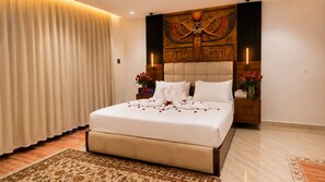 A hotel room with a large bed, a wall mural, and a nightstand with a vase of flowers. - ZEINA PYRAMIDS VIEW HOTEL (Giza)
