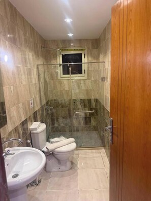 Un baño con inodoro, lavamanos y cabina de ducha.