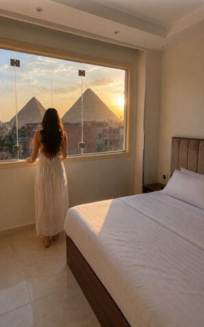 A bedroom with a large window, a bed, and a view of pyramids. - ZEINA PYRAMIDS VIEW HOTEL (Giza)