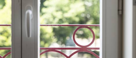 A door with a pink metal railing and a view of greenery outside.