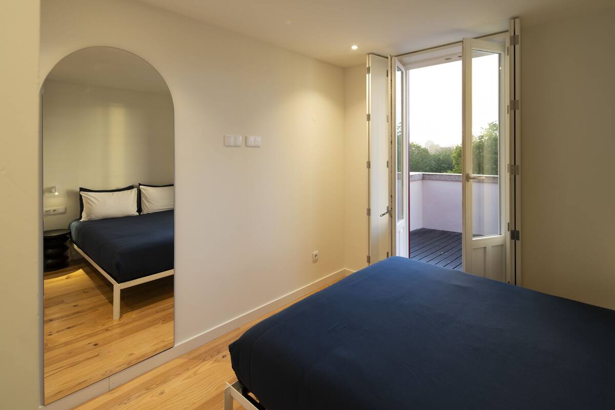Un dormitorio con cama, espejo y puerta que da a un balcón.