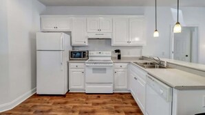 Une cuisine moderne avec des meubles blancs, un four à micro-ondes, une cuisinière et un lave-vaisselle.