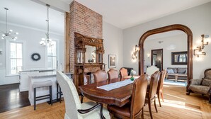 A dining room with a wooden table, chairs, and a brick fireplace.