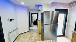 A modern kitchen with a stainless steel refrigerator, a wooden cabinet, and a tiled backsplash.