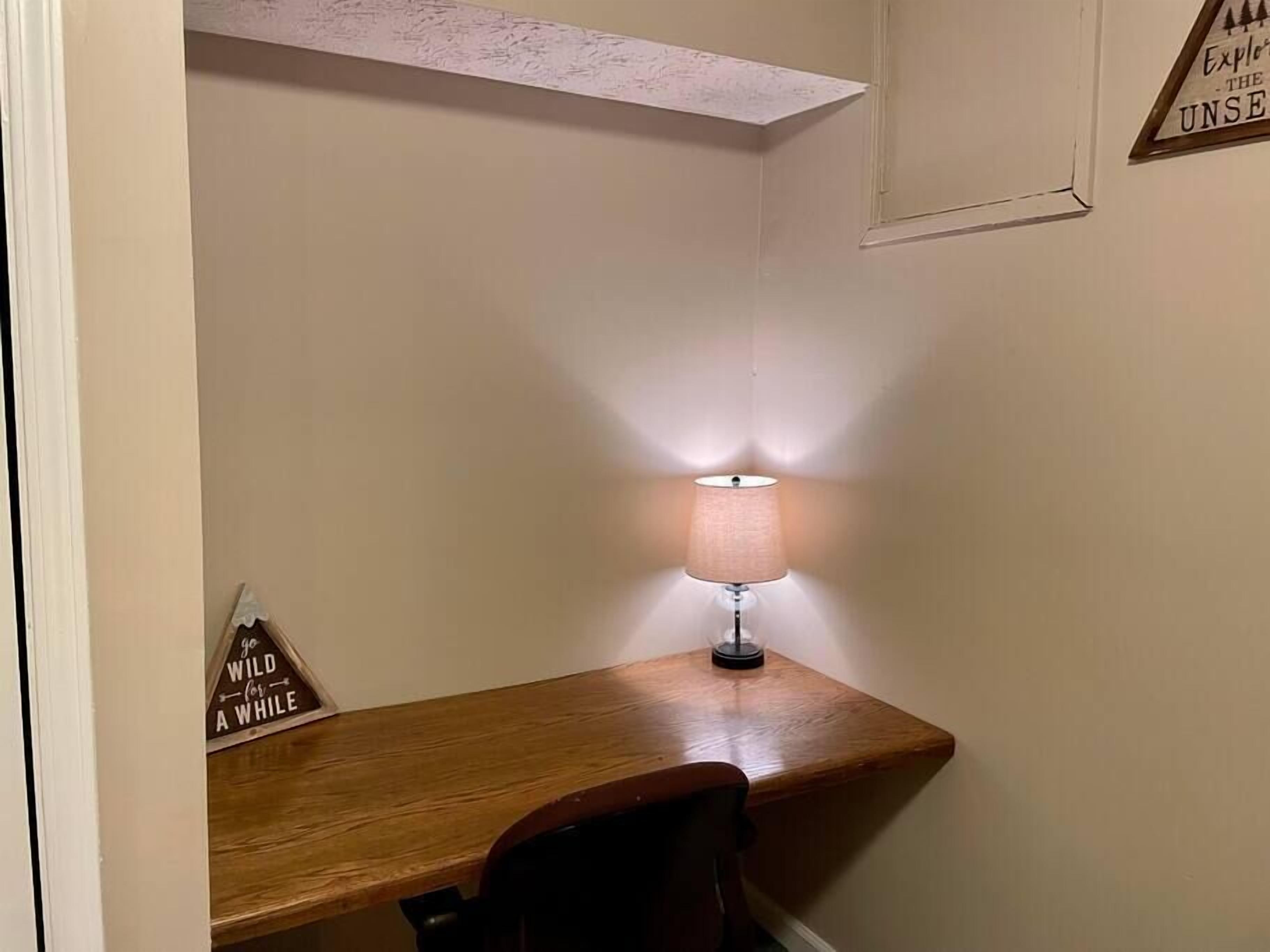 A corner desk with a lamp, a chair, and a 'go wild for a while' sign.