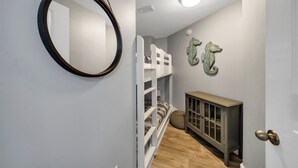 A hallway with a bunk bed, a cabinet, and a mirror on the wall. - EscapetoWaterscape-Family Friendly 2/2.5 condo (Fort Walton Beach)