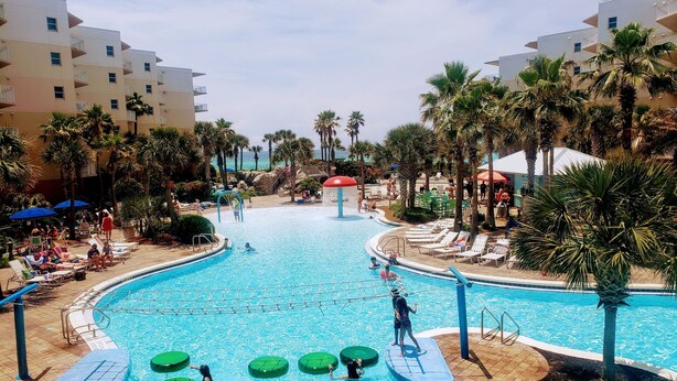 A large indoor swimming pool with multiple lanes, surrounded by palm trees and lounge chairs. - EscapetoWaterscape-Family Friendly 2/2.5 condo (Fort Walton Beach)