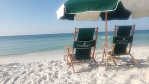 Two beach chairs under a green and white umbrella on a sandy beach with a clear view of the ocean. - EscapetoWaterscape-Family Friendly 2/2.5 condo (Fort Walton Beach)
