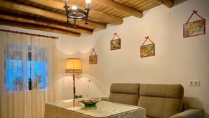Un salón acogedor con un sofá, una mesa con lámpara y una ventana con cortinas.