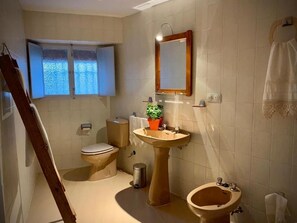 A bathroom with a toilet, bidet, pedestal sink, and a window with frosted glass. - Casa Rural Sierra Tórtola 1 (Hinojales)
