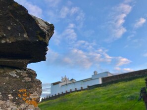 A stone structure with a clear sky and a distant building. - Casa Rural Sierra Tórtola 1 (Hinojales)