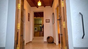 Un pasillo con puertas de madera, una lámpara en el techo y una maceta rústica en el suelo.