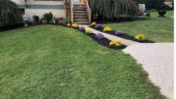 A two-story house with a front porch, a satellite dish, and a well-maintained lawn with flower beds. - Der Dawdy Haus (Narvon)