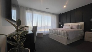 Una camera d'albergo moderna con un grande letto, una scrivania, una sedia e una pianta in vaso.