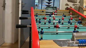 Una mesa de fútbolín en una habitación con paredes de piedra y vistas a una escalera.