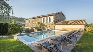 Un edificio de piedra con piscina y tumbonas.