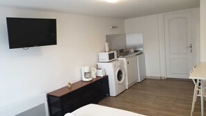 Une chambre d’hôtel compacte équipée d’un téléviseur à écran plat fixé au mur, d’un lave-linge, d’un four à micro-ondes et d’une machine à café posée sur le comptoir.