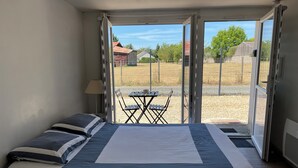 Une chambre avec un lit, une table et des chaises, située devant une porte-fenêtre coulissante.