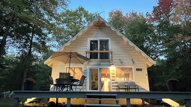A two-story log cabin with a deck and outdoor seating area.