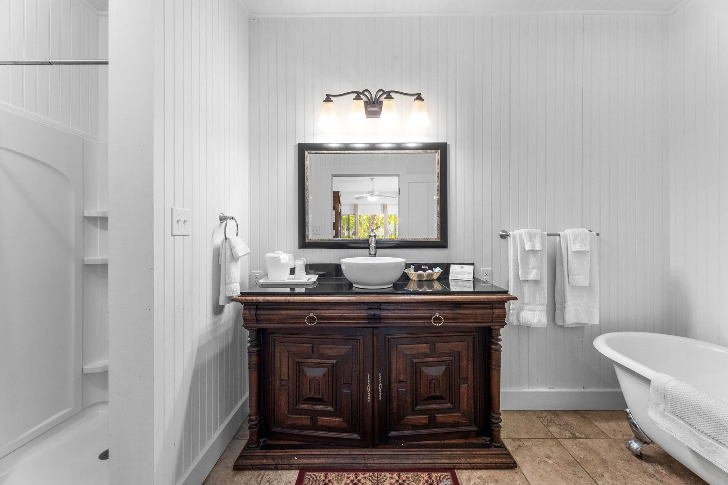 Une salle de bain avec un meuble-lavabo en bois foncé, un lavabo blanc et une baignoire blanche.