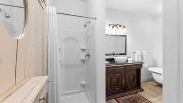 A bathroom with a shower, a sink, a toilet, and a mirror.