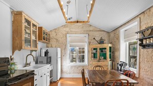 A kitchen with wooden cabinets, a dining table, and chairs. There is a window with a view outside. - Meyer Hotel (Comfort)