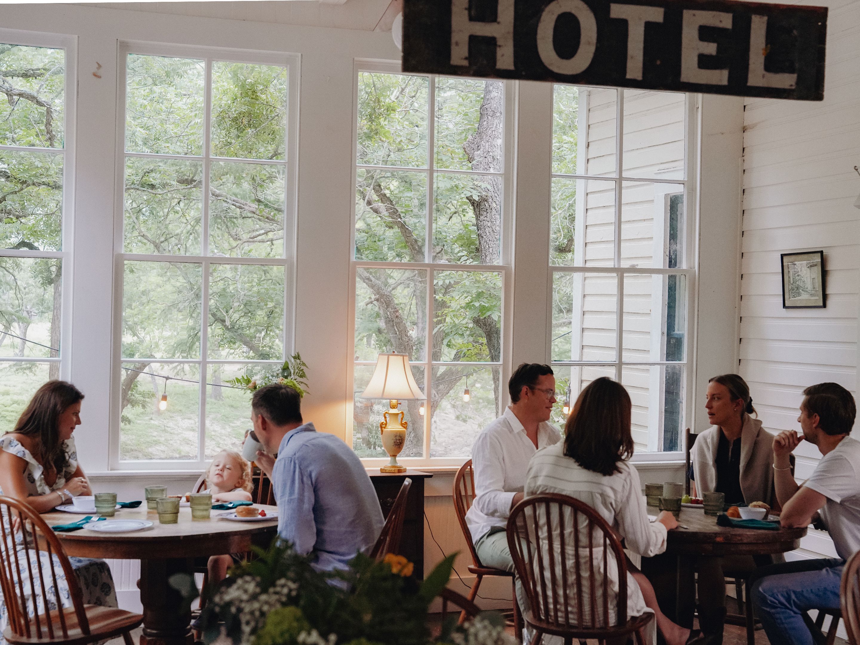 A hotel dining area with large windows, wooden furniture, and a sign reading 'HOTEL'.