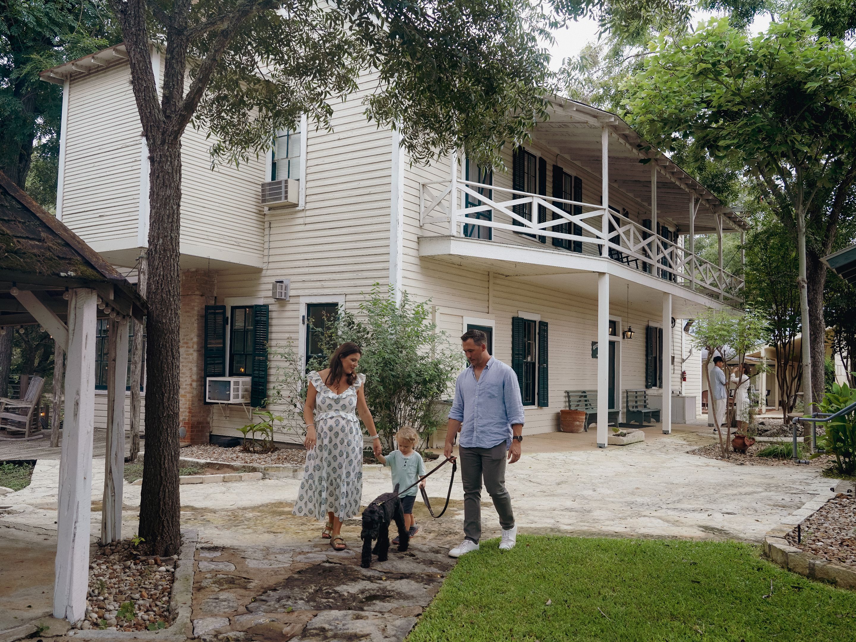 A two-story house with a covered porch, a small garden, and a paved walkway.