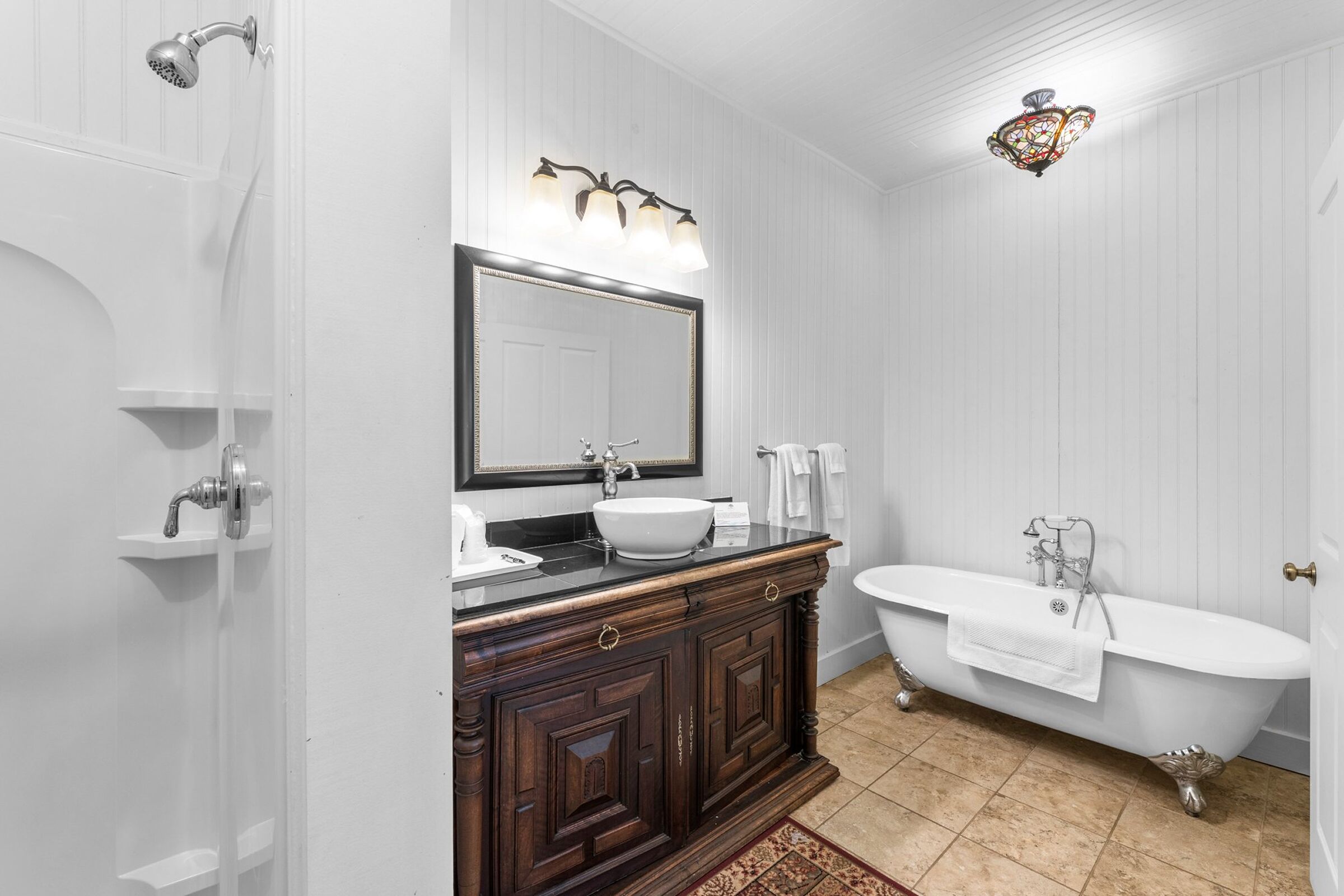A bathroom with a freestanding bathtub, a vanity with a mirror, and a shower.