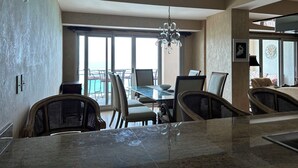 A dining area with a glass table, chairs, and a chandelier.