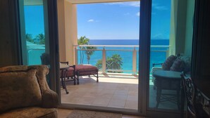 A balcony with a view of the ocean, a chair, and a sofa.