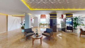 A spacious lobby with a modern design, featuring two sofas, a coffee table, and a glass partition.