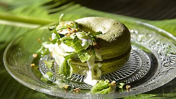 A sandwich on a decorative glass plate with a leaf pattern, placed on a green tablecloth.