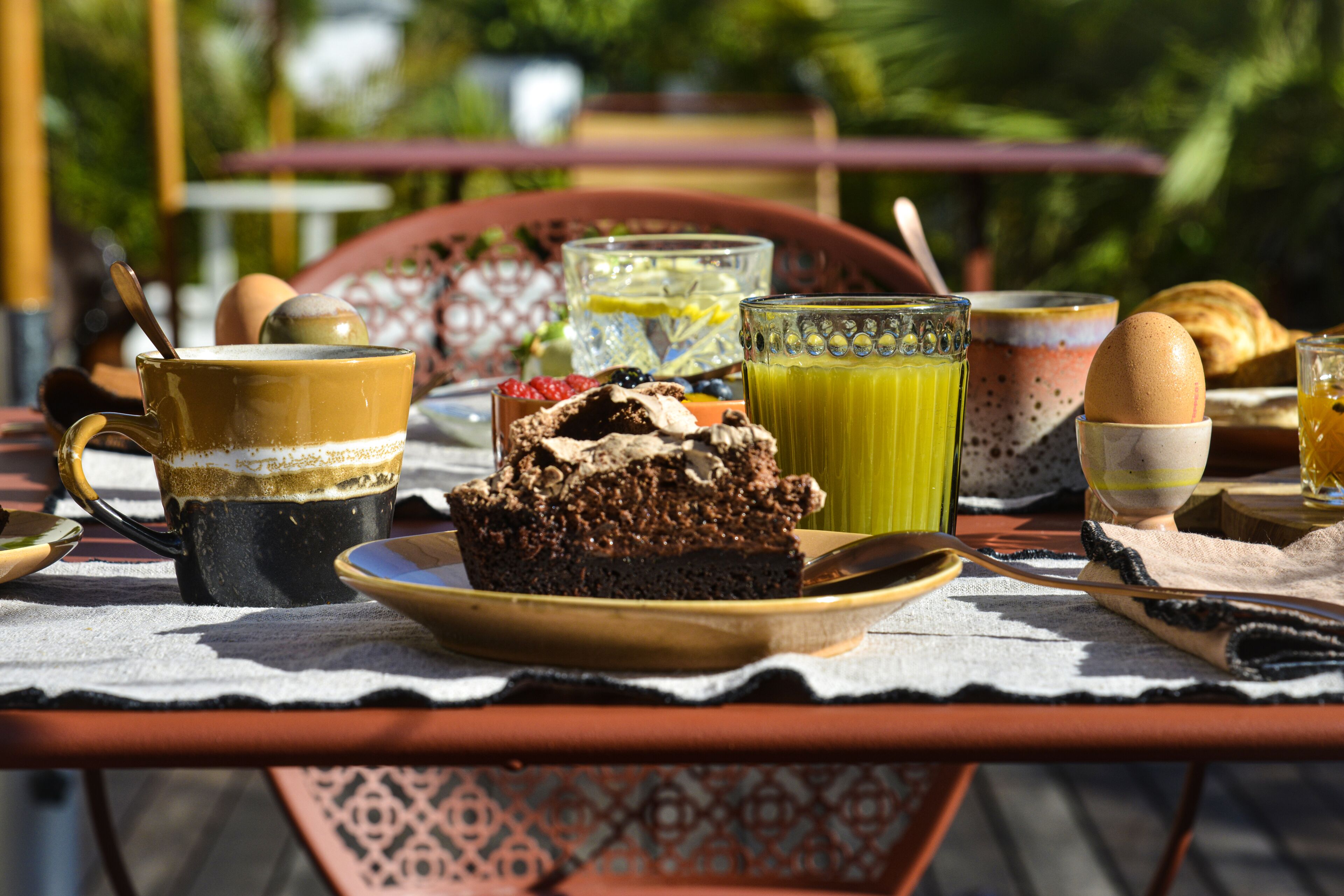 Una mesa con diversas opciones de desayuno, como una porción de pastel, un vaso de jugo y una taza de café.