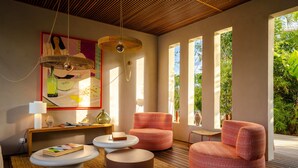 A modern living room with a wooden ceiling, large windows, and a view of greenery. - Le Martin Boutique Hôtel (Cul de Sac)