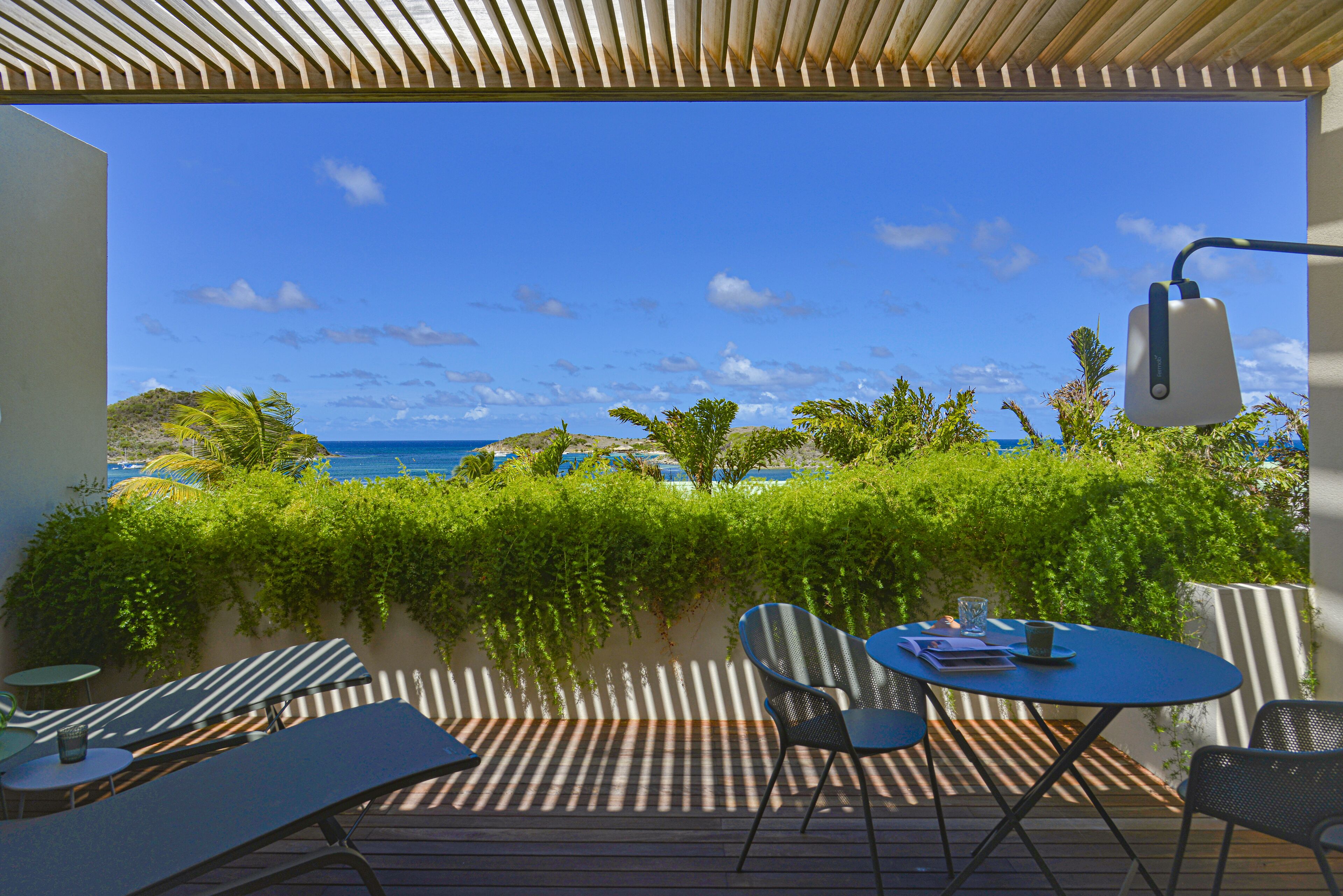 Terraço com vista para o mar, com mesa, cadeiras e um abajur.