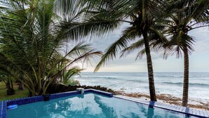 A pool with a view of the ocean and palm trees. - Luxury Oceanfront Villa Vega Baja: 2 Pools, Waterslide + Tennis/Pickleball court (Vega Baja)
