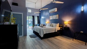 A bedroom with a bed, ceiling fans, wall-mounted air conditioning, bedside lamps, and a view through a glass door. - Luxury Oceanfront Villa Vega Baja: 2 Pools, Waterslide + Tennis/Pickleball court (Vega Baja)