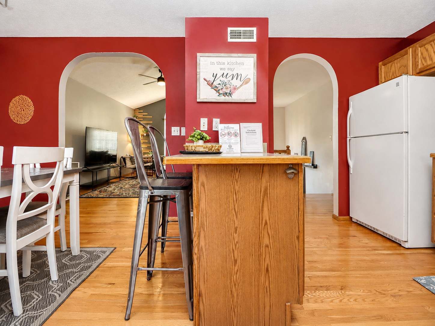 A compact kitchen with a wooden island, white refrigerator, and red walls.