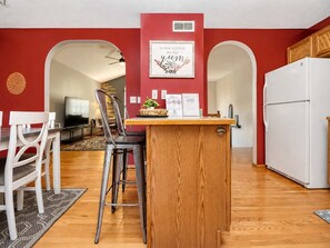 A compact kitchen with a wooden island, white refrigerator, and red walls. - Pet-friendly home near UNL with game room (Lincoln)